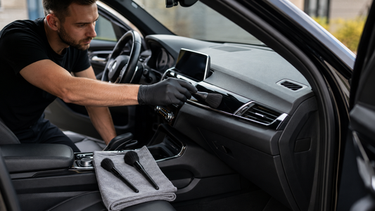 Soft detailing brush cleaning an air vent inside a modern black car interior